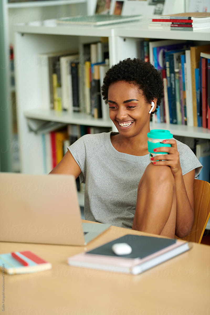 Smiling black student using laptop.