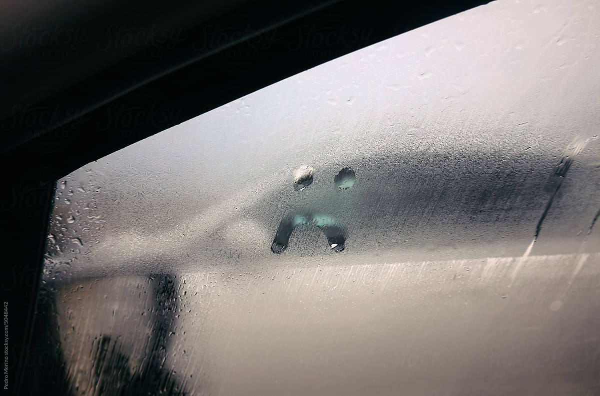 Sad face in the fog of the car window