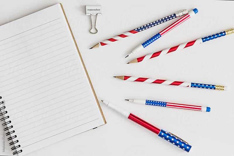 Blank notebook, stars and stripes pens and pencils and paper clip saying \