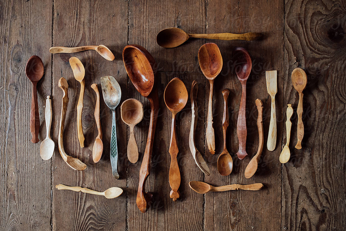 A collection of carved wooden spoons displayed on a wood floor.