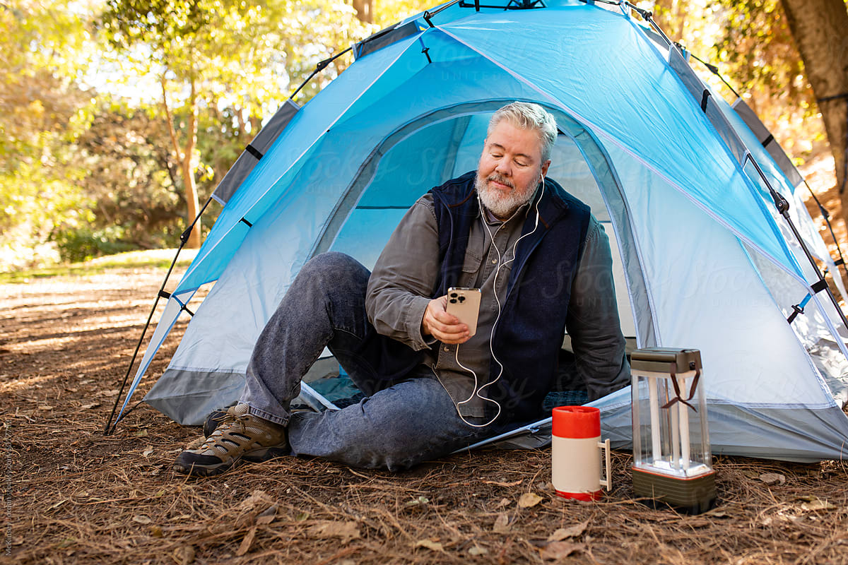 Man Uses Headphones While Sitting In His Tent Out In Nature
