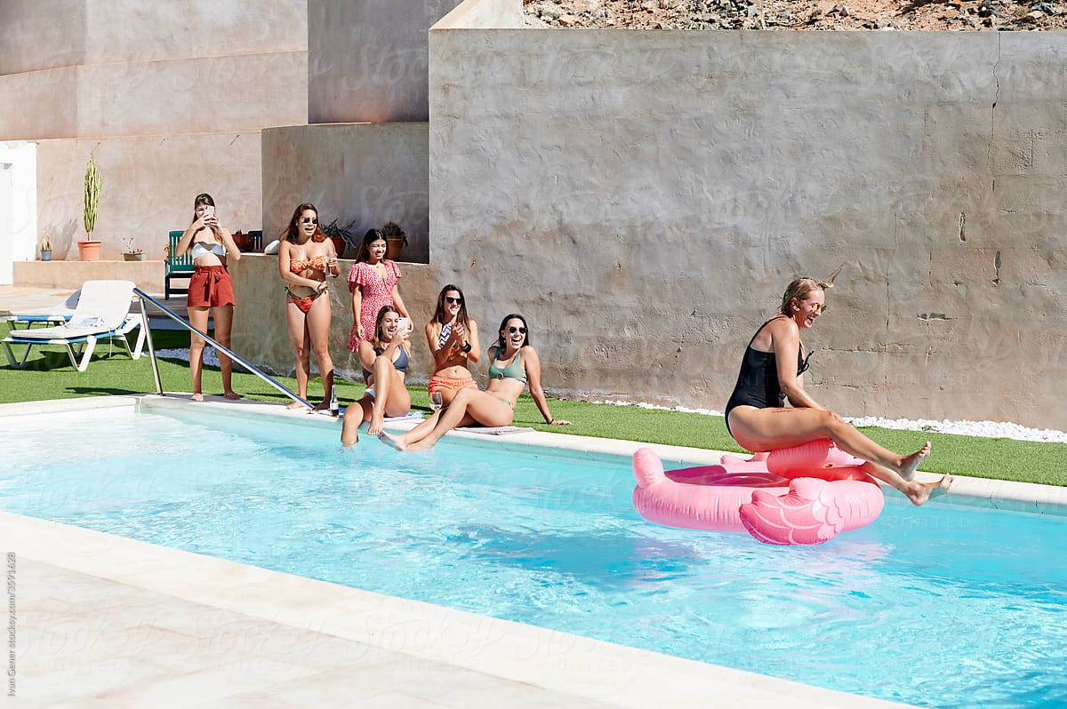 Women taking photos of a friend on a pool float