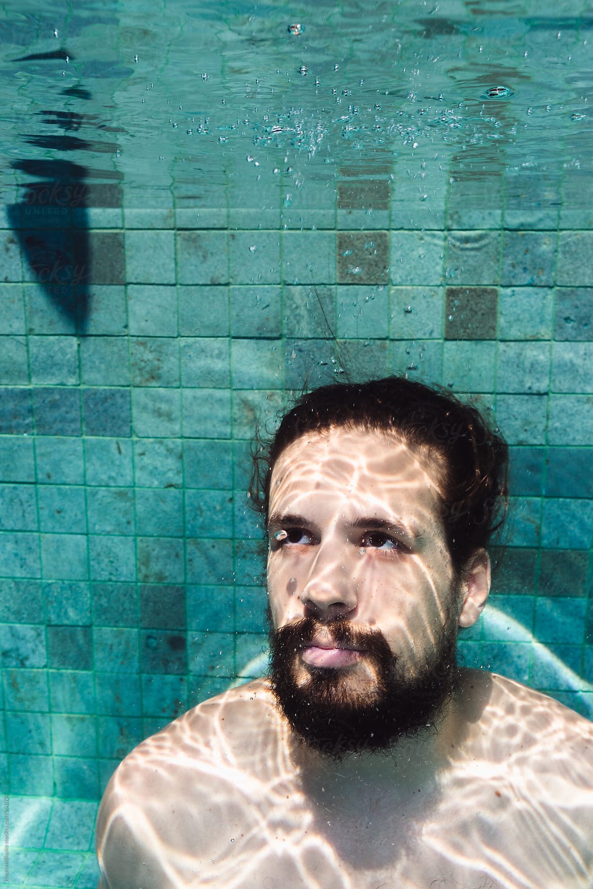 Portrait of a man holding his breath underwater looking up at the surface