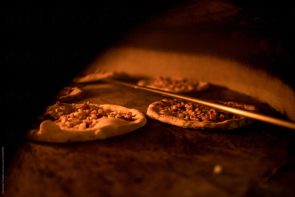 A traditionally made pizza going into a wood fire oven