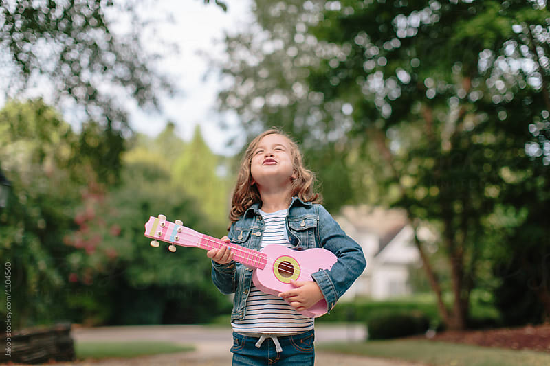 Adorable young girl singing and playing her toy guitar