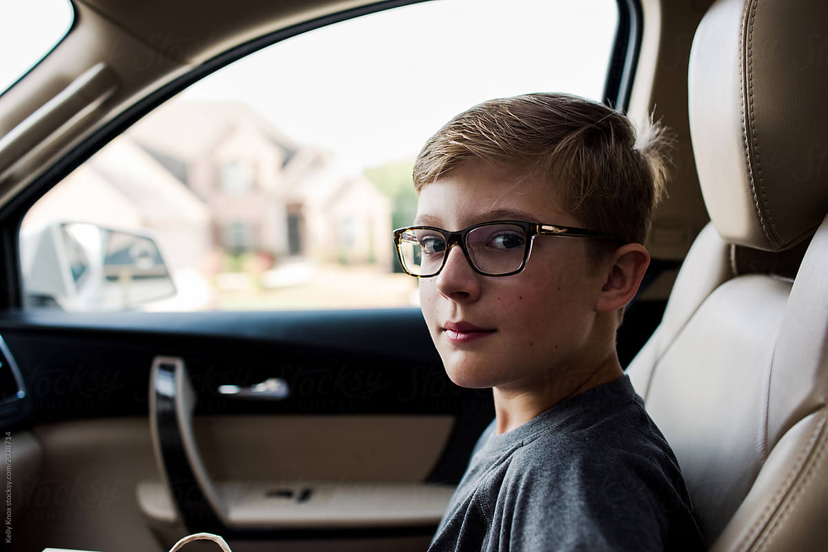 portrait of a handsome middle school aged boy riding in the passenger seat of a car