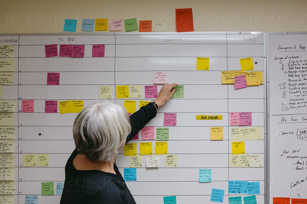 Mature caucasian woman at work in office putting up sticky notes