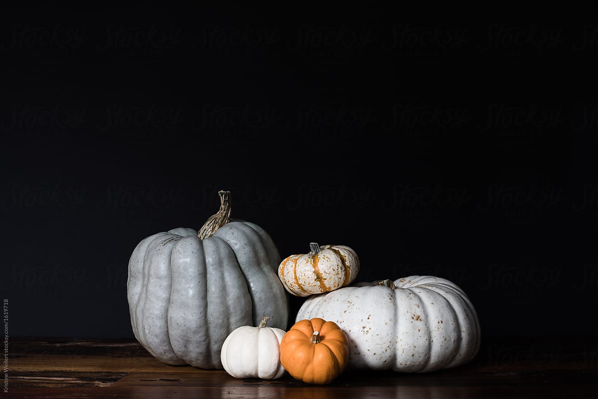 Variety of pumpkins stacked on table with dark background