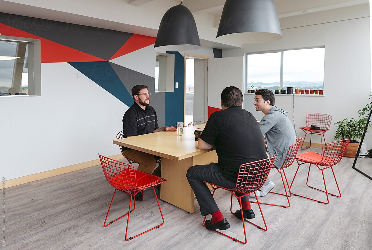 Three men meeting at kitchen table in office environment