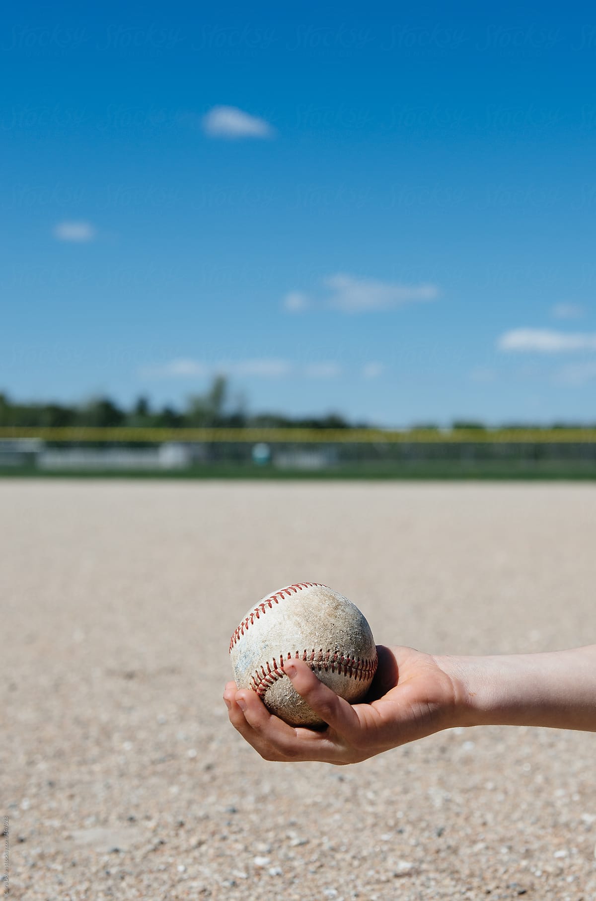 Child\'s arm with baseball on athletic field