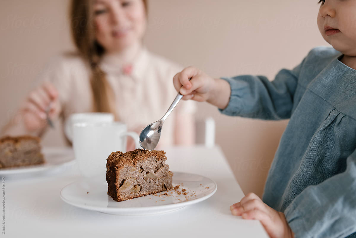 Little girl taking piece of chocolate cake by spoon.