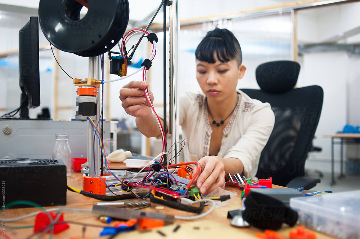 Young adult woman on her working desk in workshop and 3d printer