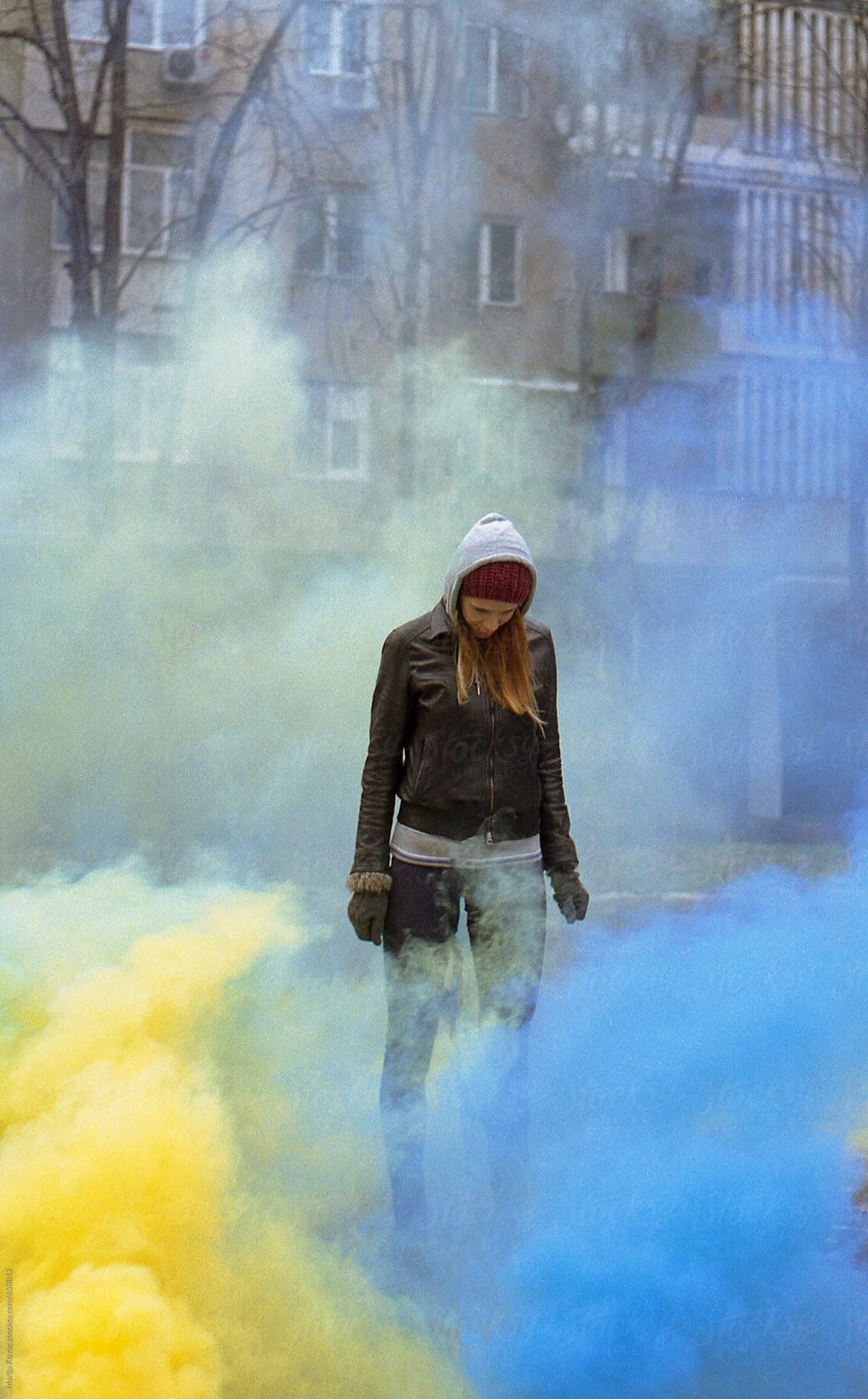 Young woman looking in a blue and yellow smoke