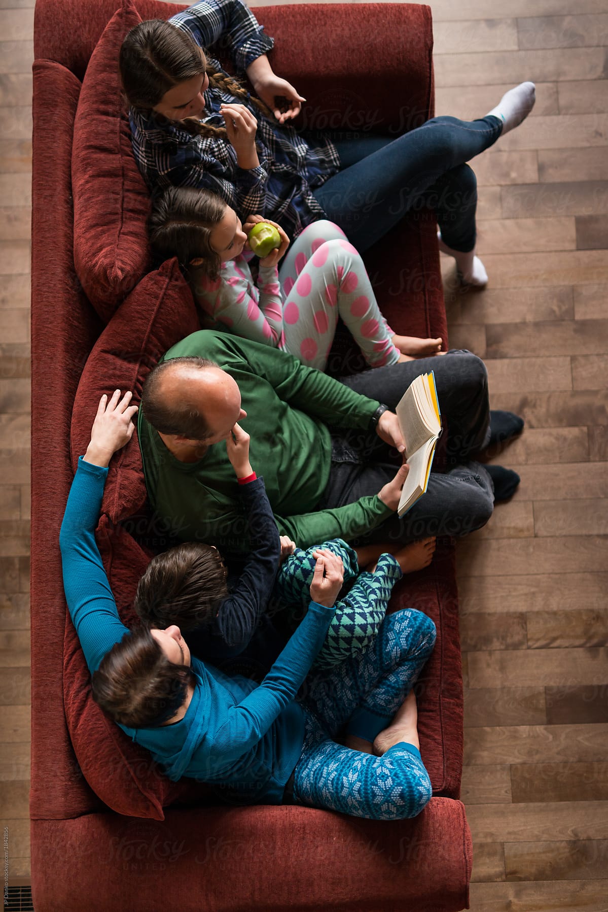 Overhead view family in ski chalet relaxes on sofa