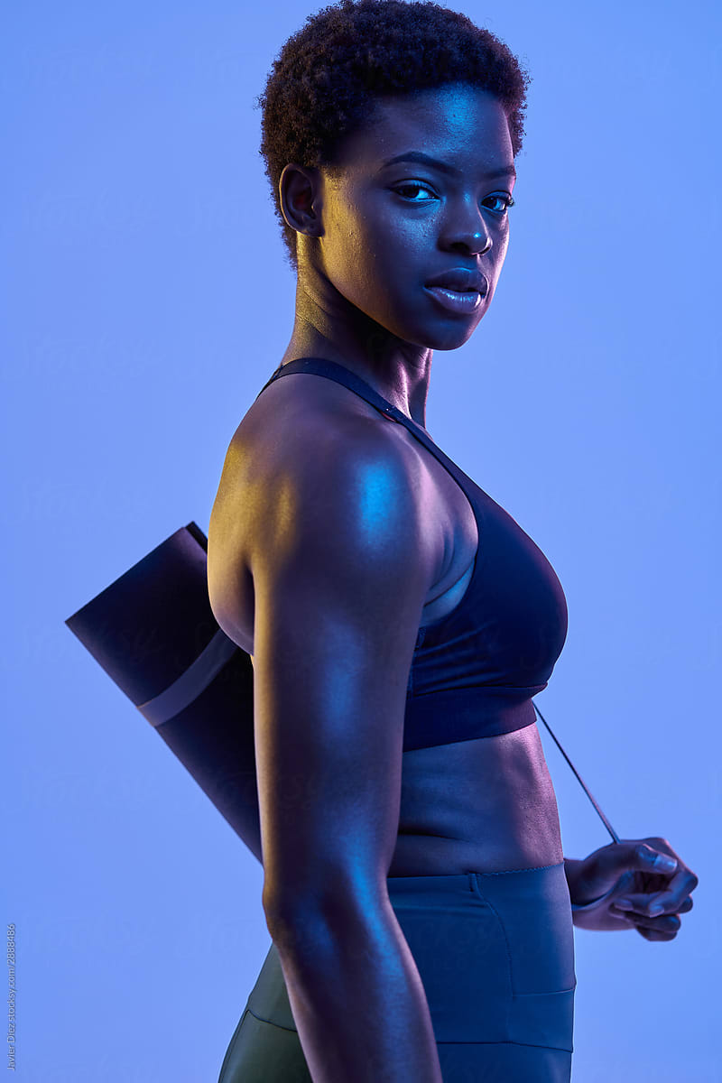 Confident black sportswoman with mat