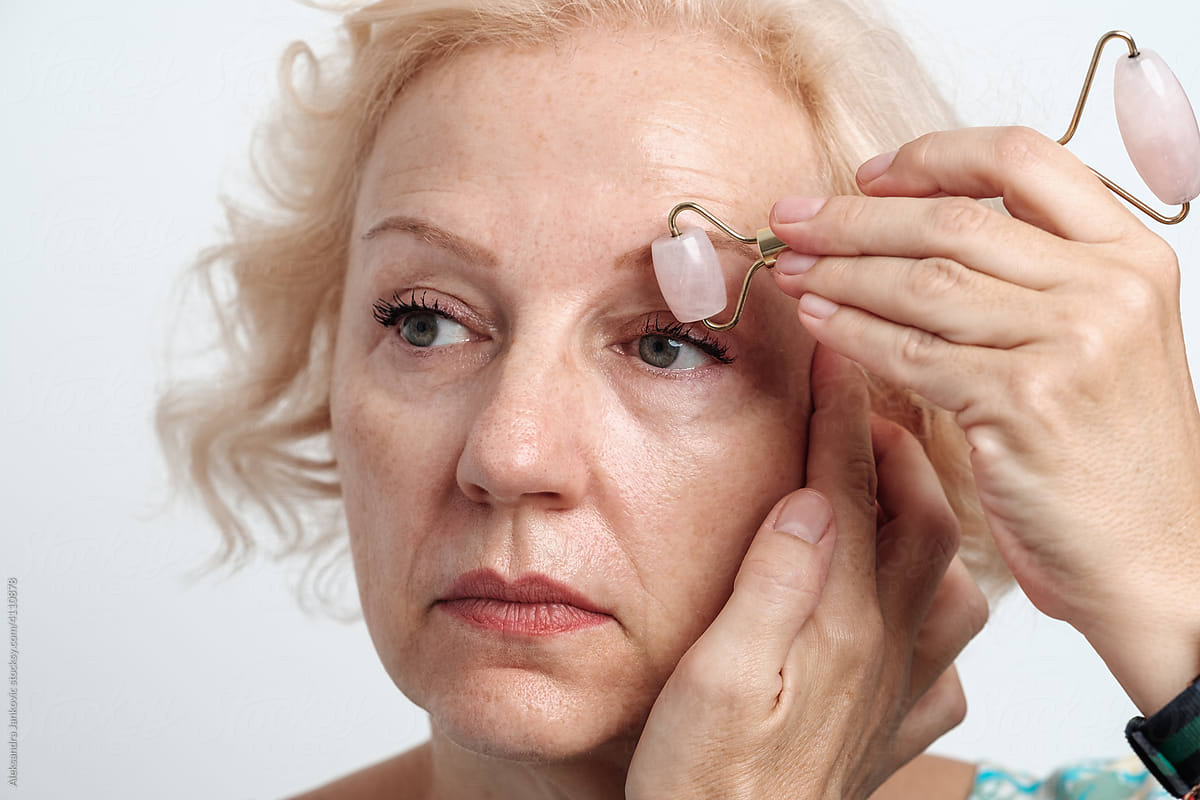 Middle Aged Woman Using Face Roller Around Her Eyes