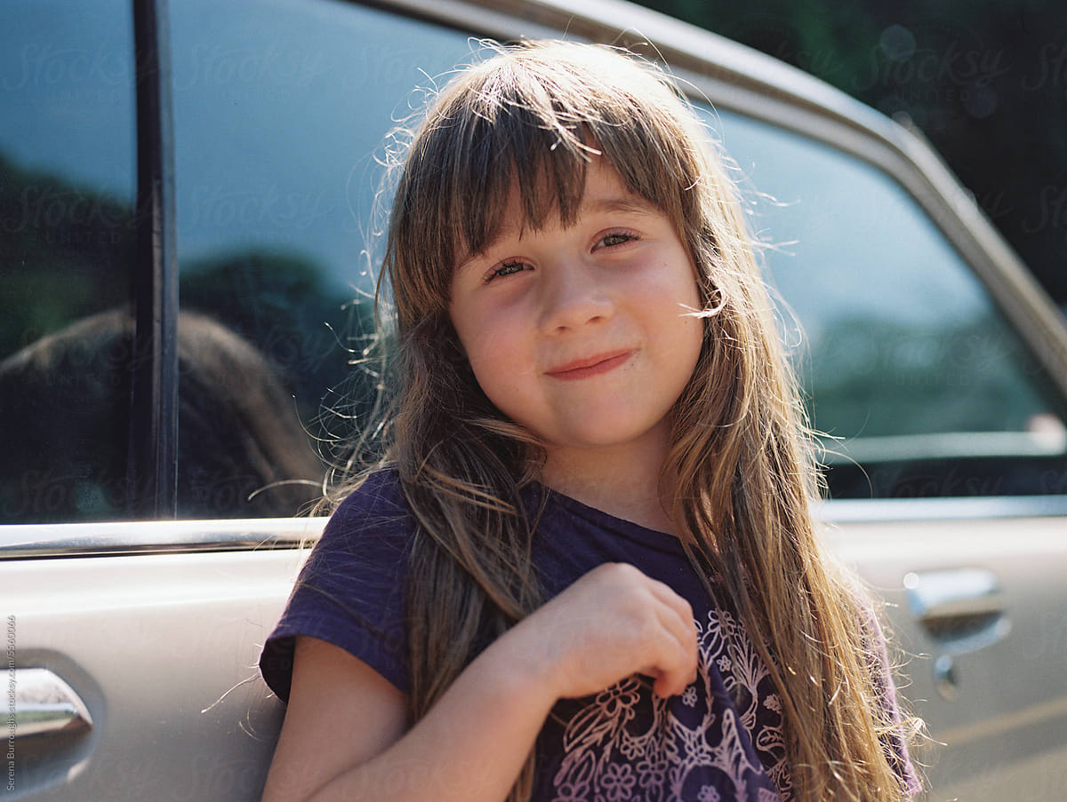 smiling girl standing outdoors by an old car in summer