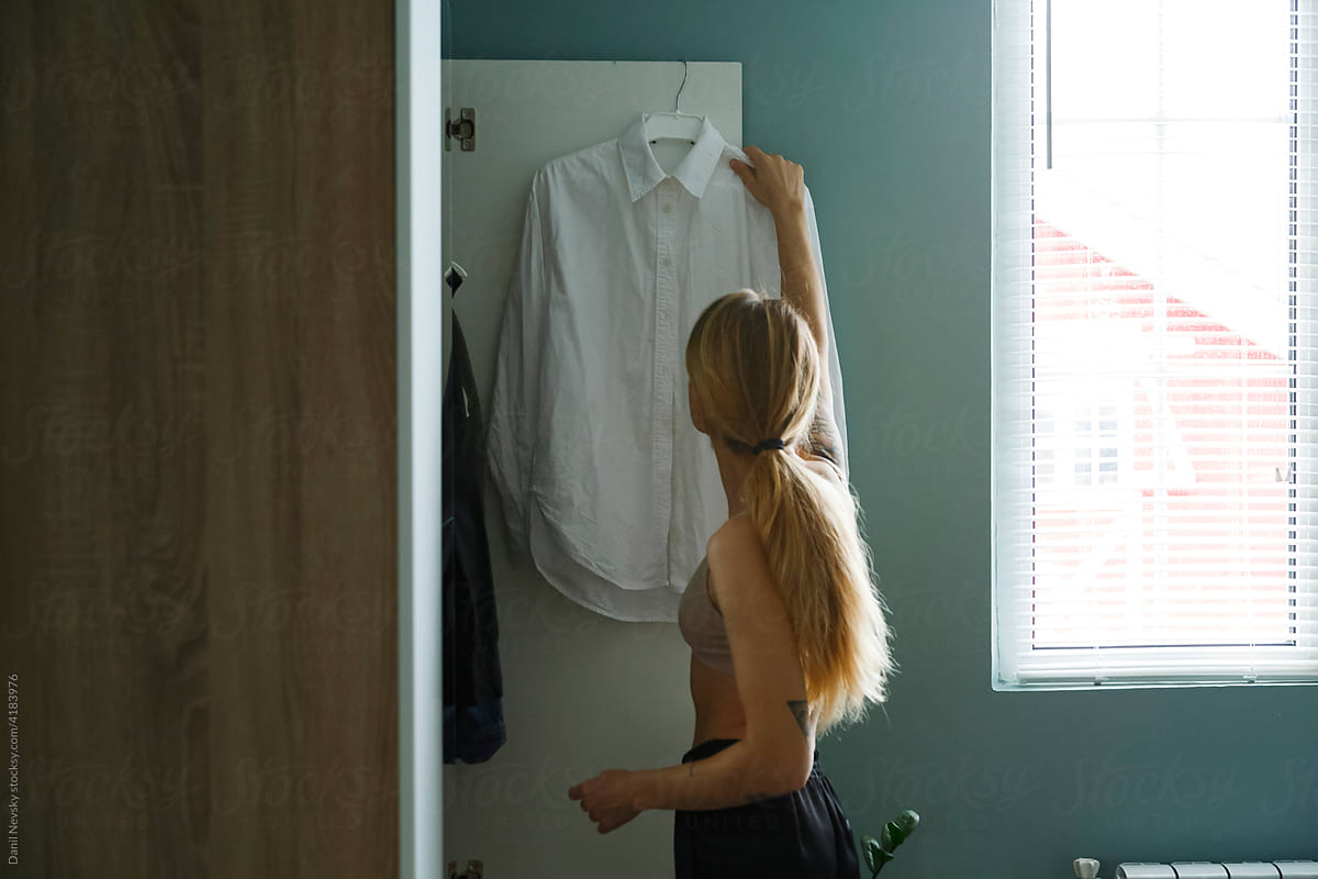 Woman taking white shirt from wardrobe