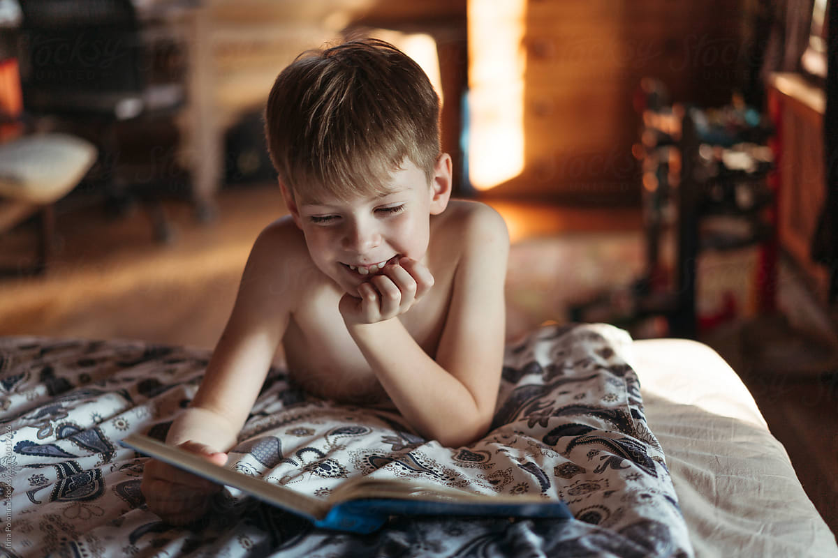 Smiling Boy Reading in Cozy Bedroom