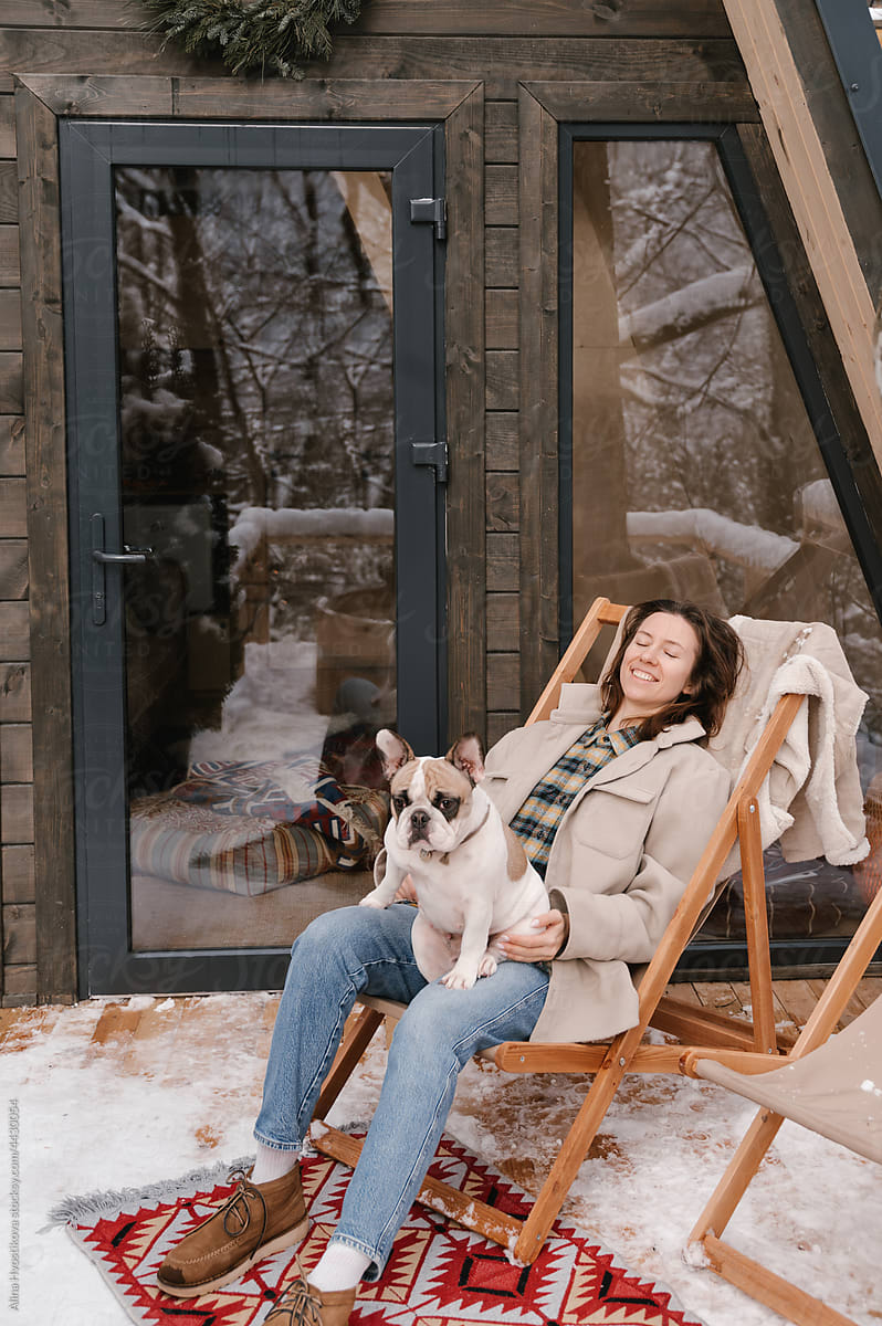 Relaxed woman with french Bulldog sitting in deckchair