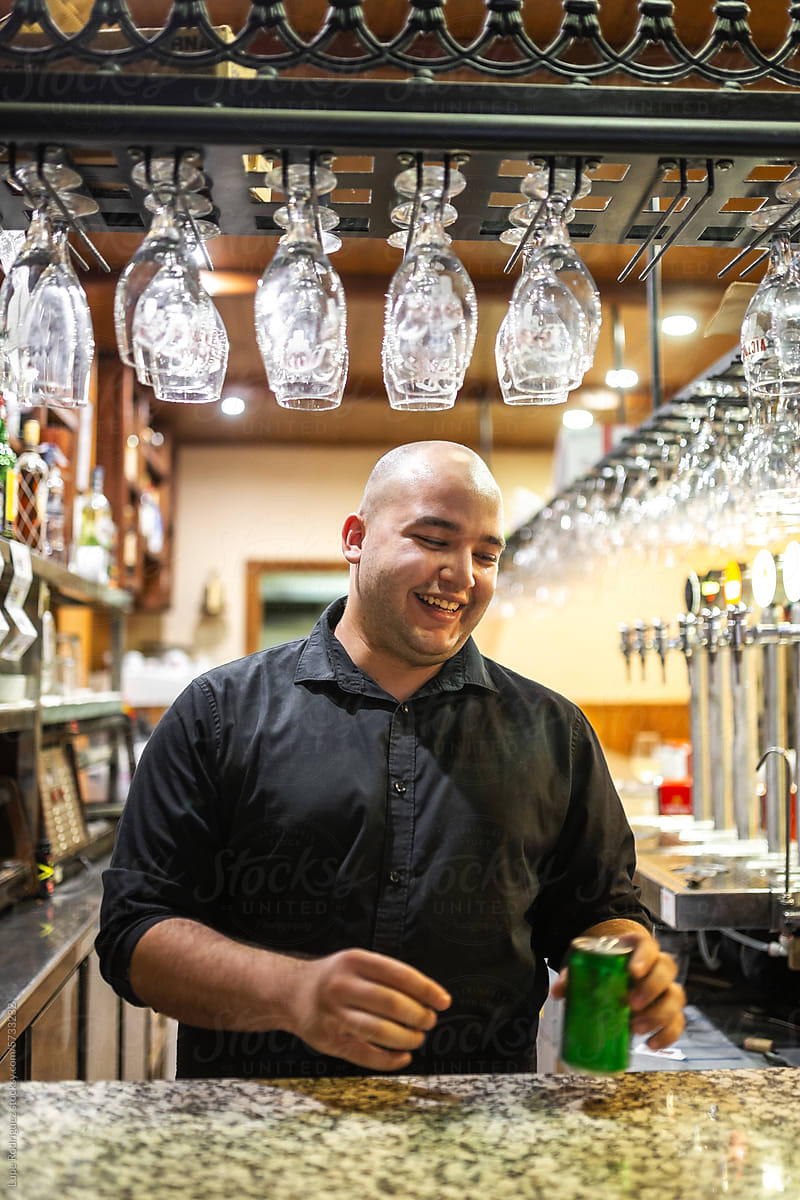 young waiter serving a soft drink at the counter of a bar