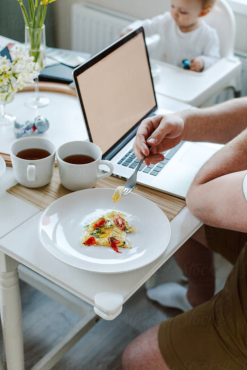 Man having breakfast while working on laptop