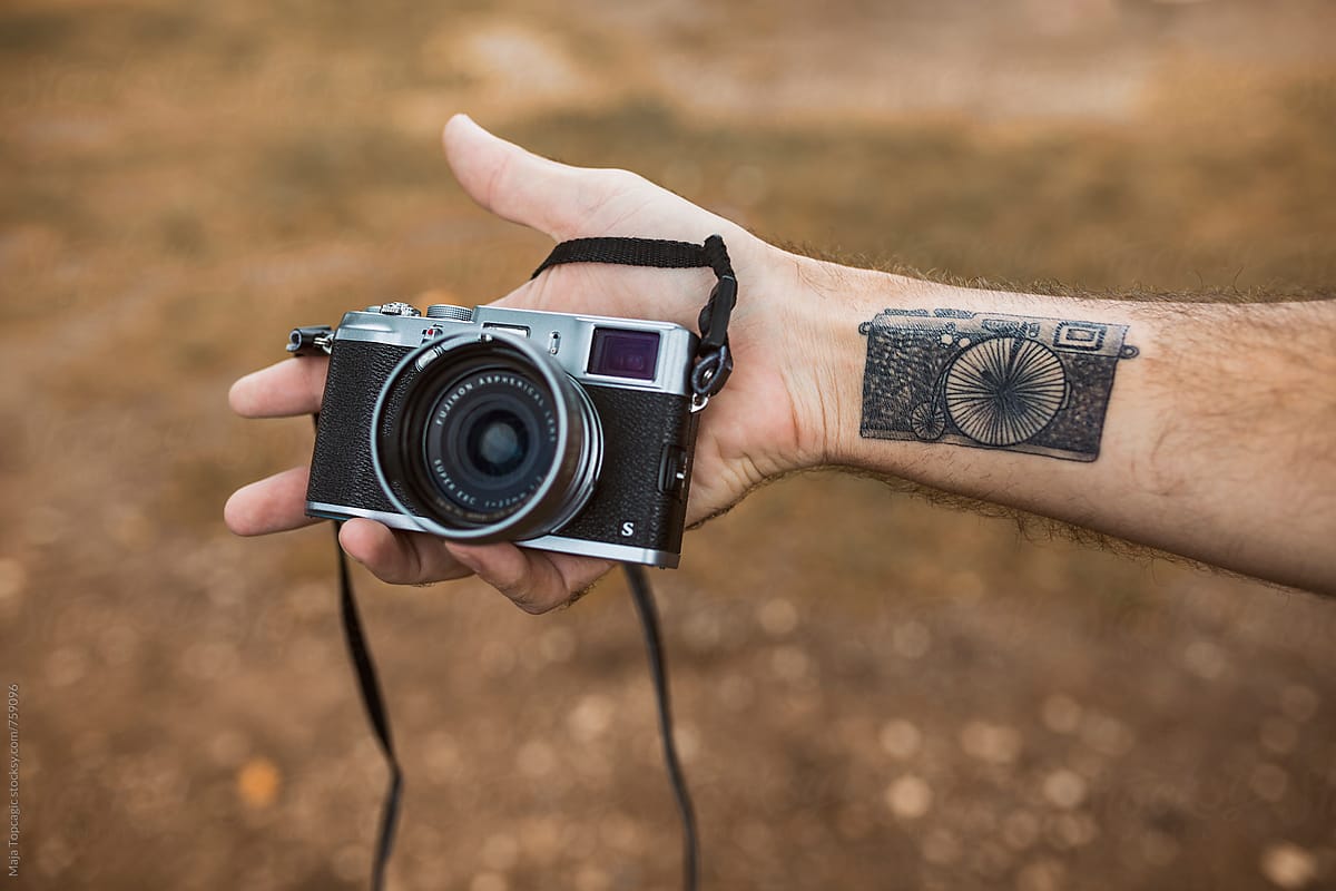 A man with a camera tattoo holding a camera