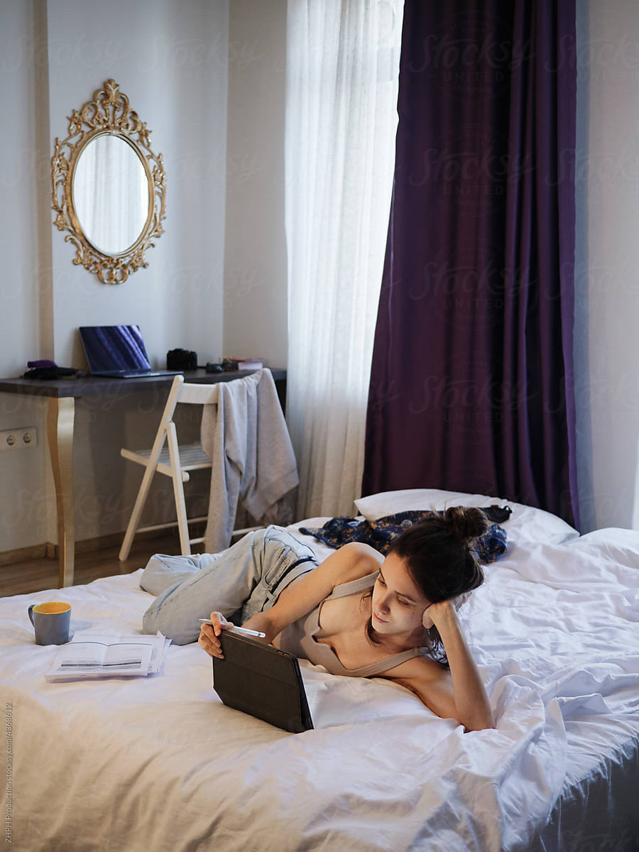 Woman works on tablet in her bed