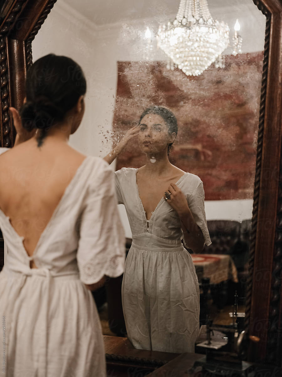 Woman in old-fashioned dress against mirror