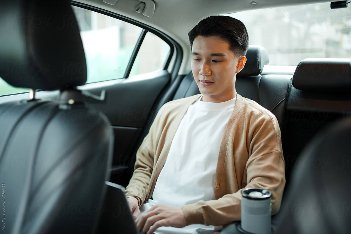 Image of young businessman working with laptop computer inside the car