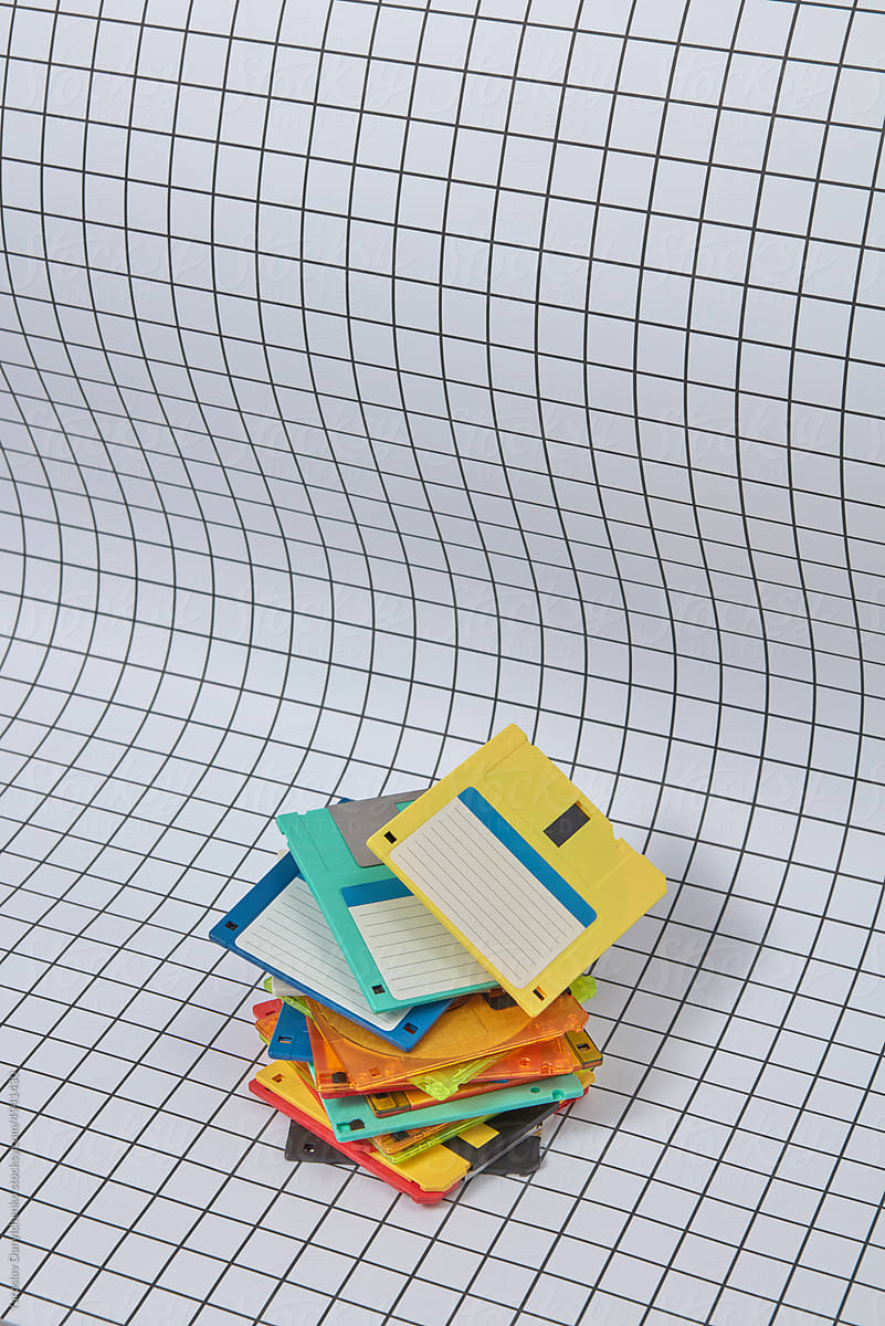 Multicolored floppy disk pile on grid background.