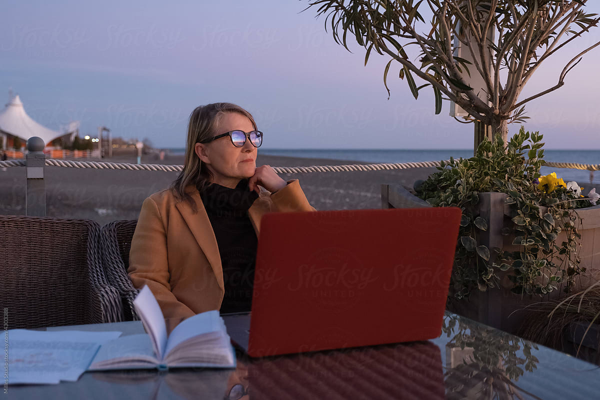 Thoughtful female freelancer on terrace on beach