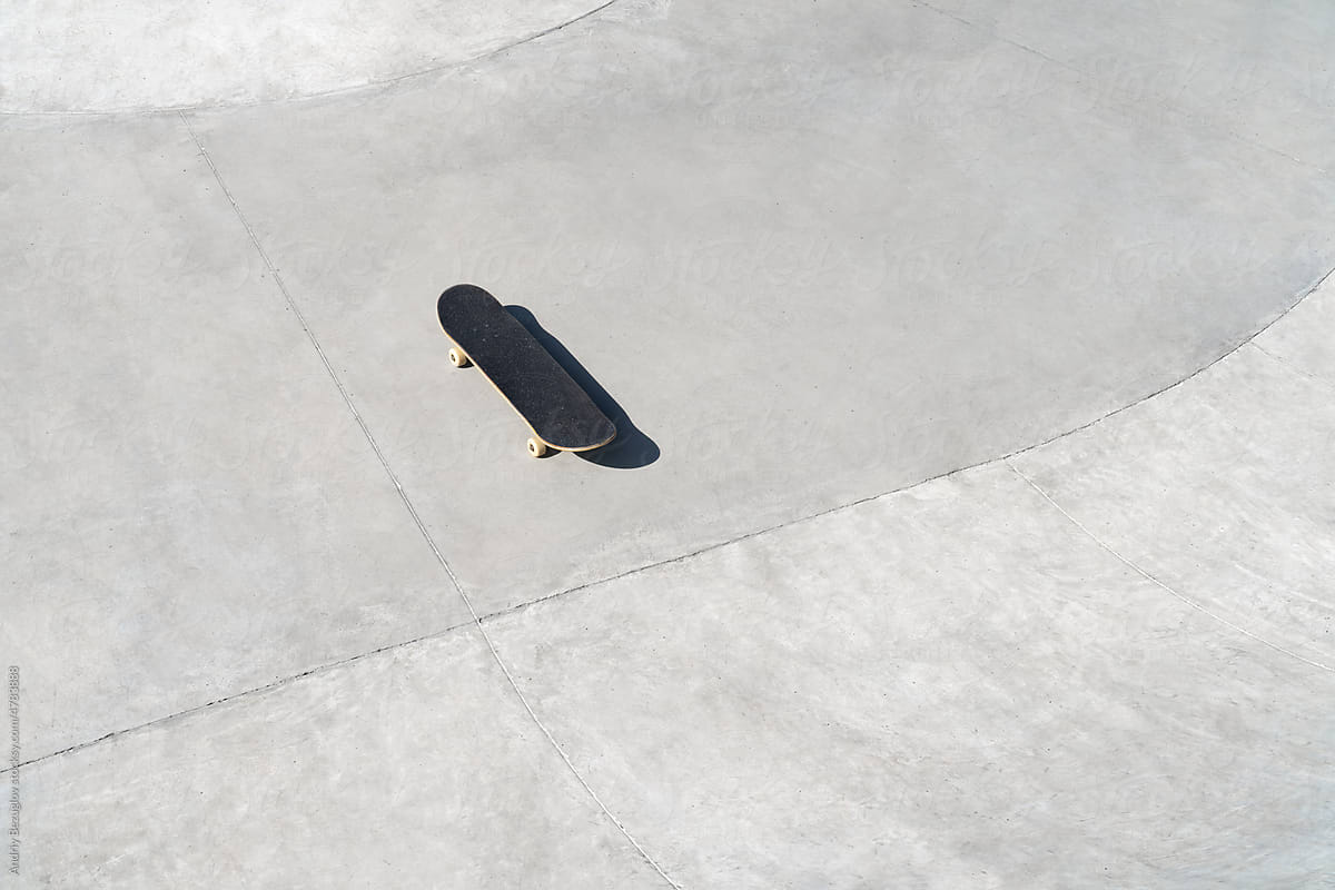 Skateboard stands on a concrete surface in a skate park.