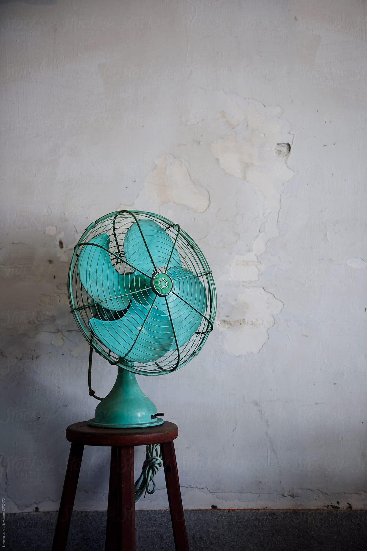 Still life of blue fan on wooden stool against of shabby wall