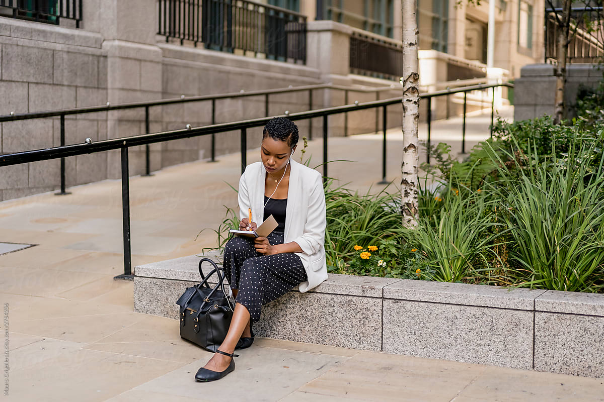 Black Woman sitting outdoor and writing