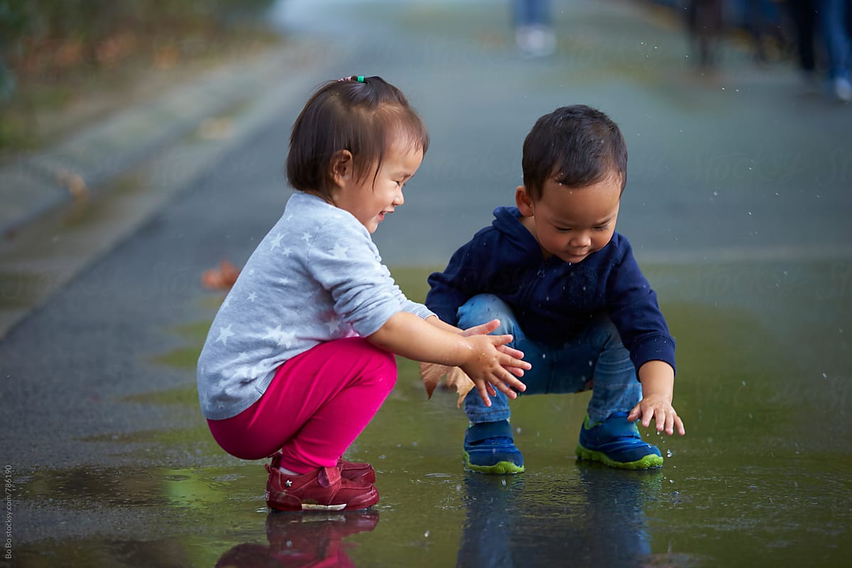 two lovely little kids playing on wet road