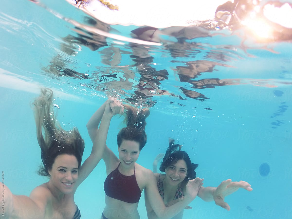 Three friends in bikini swimming in pool underwater