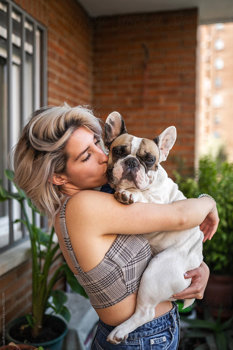 young woman hugging her french bulldog dog at home