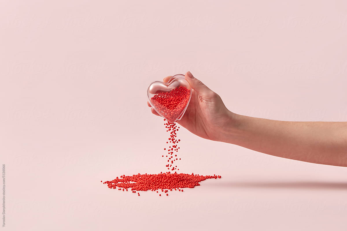 Glass heart in hand, red balls falling out.