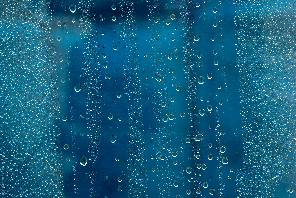 Macro closeup of raindrops water droplets on glass, colors from background