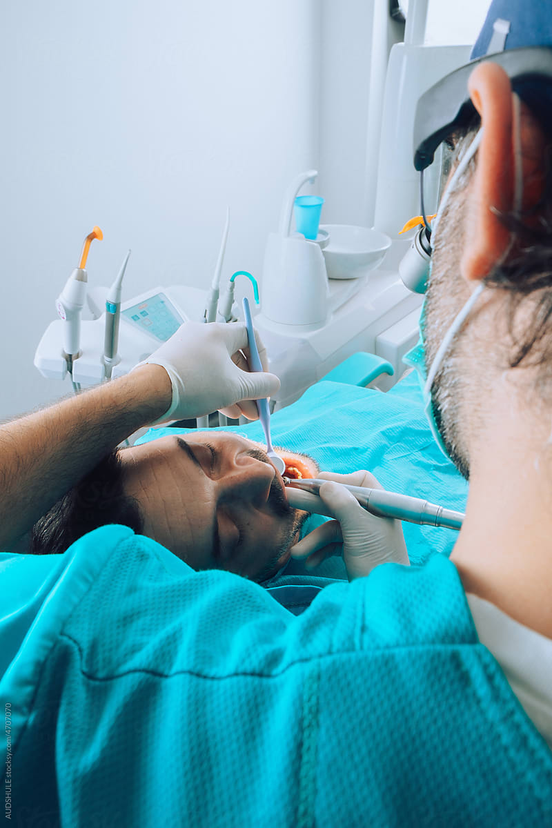 Dentist using various instruments on patient teeth