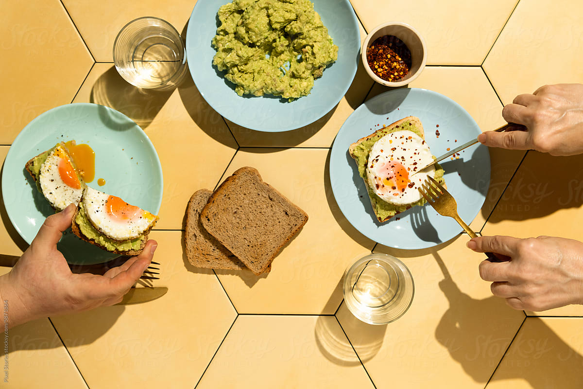 Two people having breakfast with avocado egg toasts