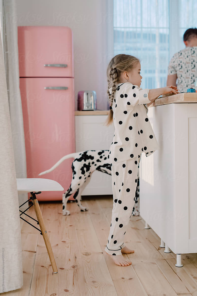 Kid with her dad and a Dalmatian dog in the kitchen with pink fridge