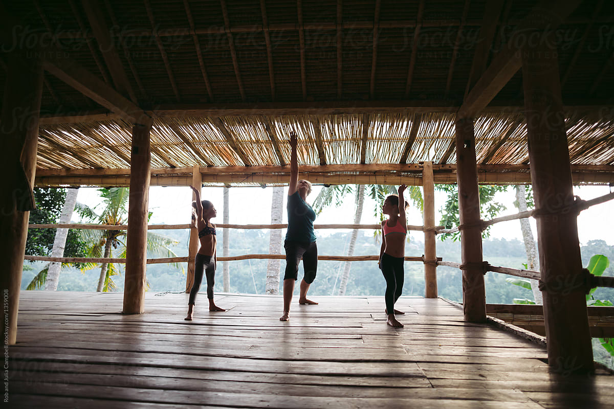 Energetic grandma teaching grandkids yoga in tropical vacation h