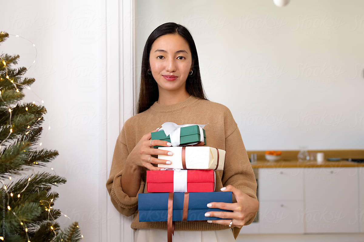 A young woman holds several colorful boxes with Christmas gifts
