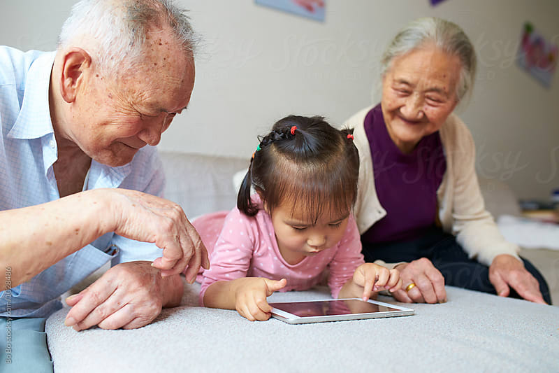 little asian girl using tablet indoor with her great grandparents