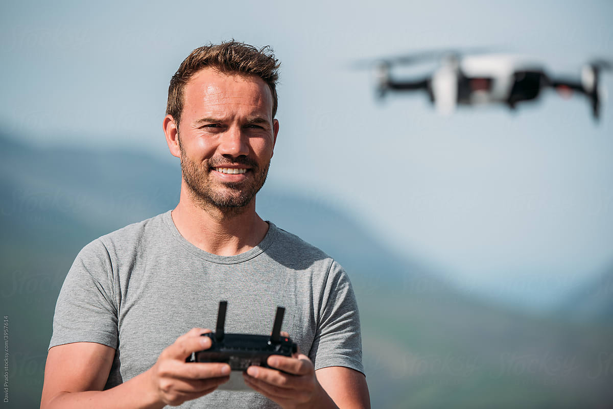 Positive male traveler controlling UAV copter
