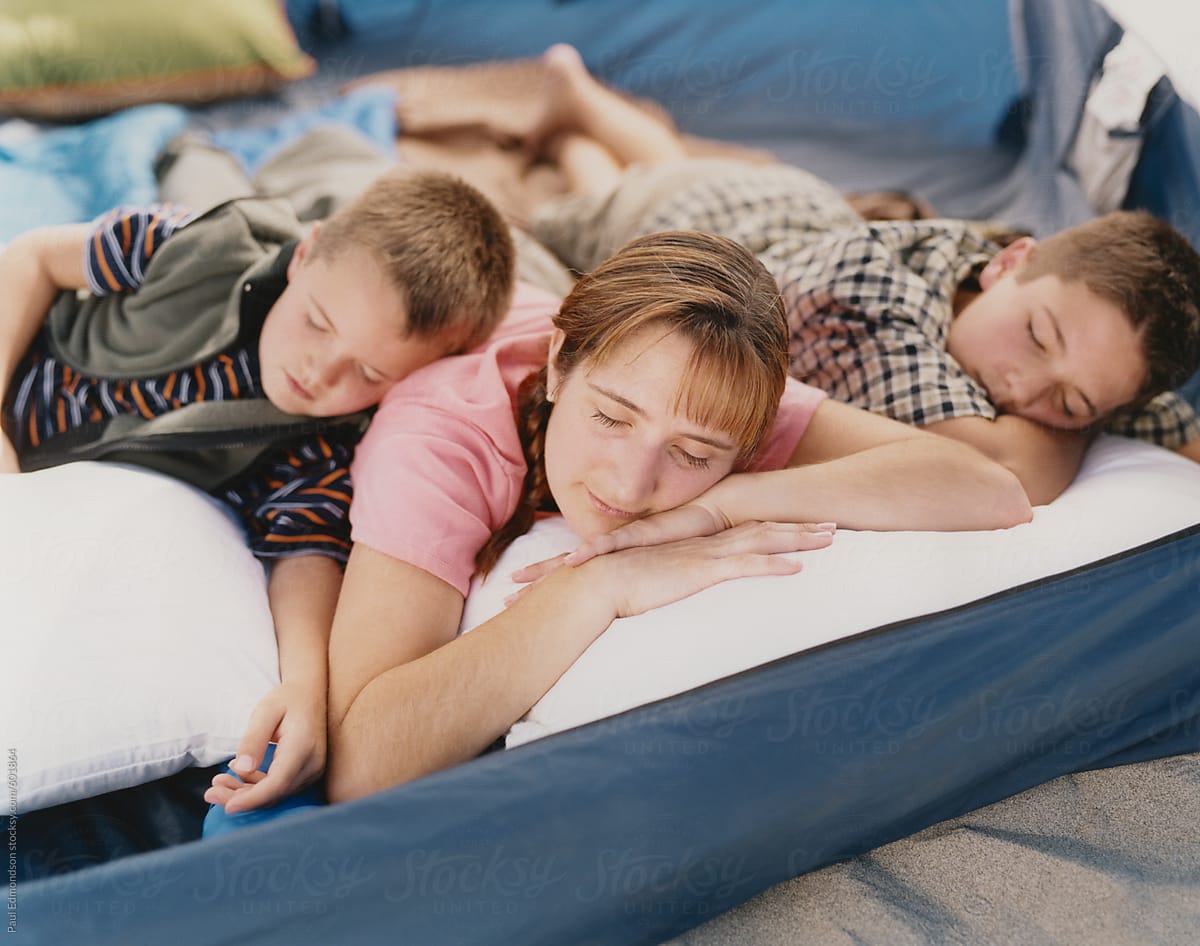 Mother and sons sleeping together in camping tent by Rialto Images ... picture