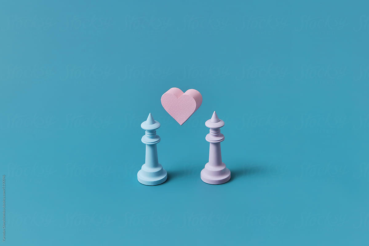 Two chess pieces with pink paper heart between.