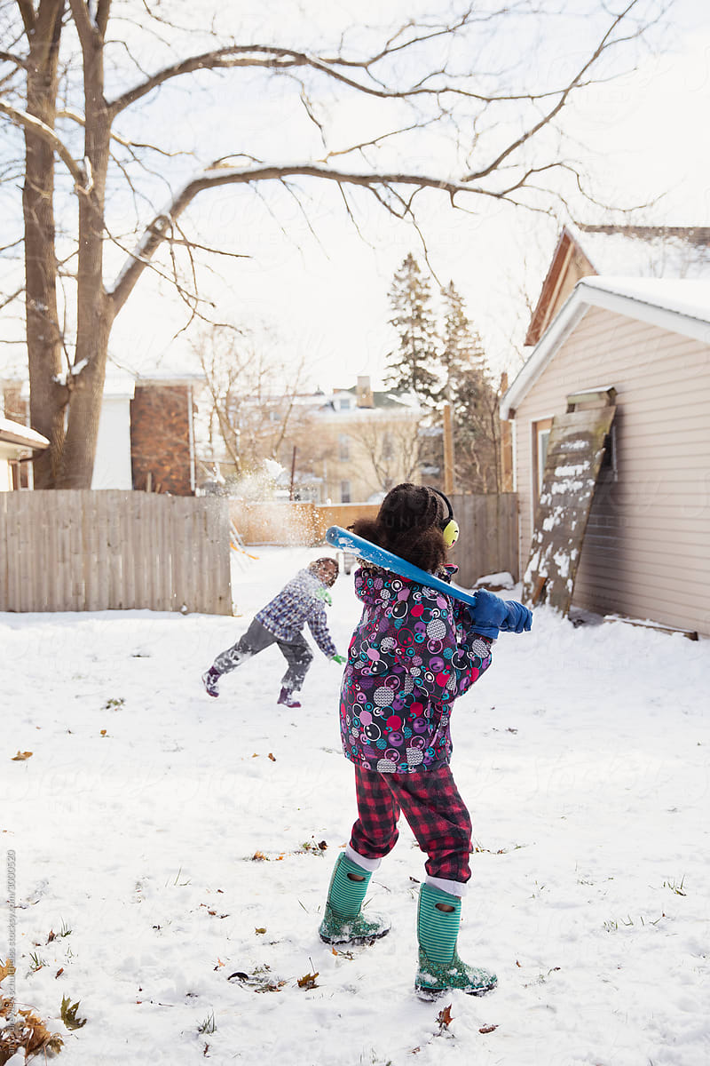 Children playing baseball outside in the winter snow